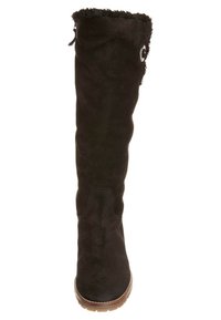 Bota alta hasta la rodilla de ante negro con una parte superior suave y con flecos, un adorno circular de plata y una suela de goma texturizada.