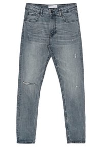 Vaqueros de mezclilla azul claro, ajustados, con un ligero desgaste y rodillas deshilachadas. Diseño clásico de cinco bolsillos con cierre de cremallera.