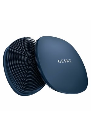 Deux brosses ovales en silicone bleu foncé pour le nettoyage du visage, l'une montrant des poils doux, l'autre une surface lisse avec la marque "GESKE".