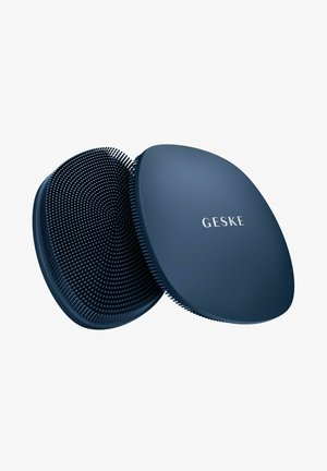 To mørkeblå ovale silikonebørster til ansigtsrensning, den ene med bløde børstehår, den anden med en glat overflade med "GESKE" branding.