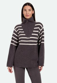 Pull en tricot gris avec des rayures horizontales crème, col montant, demi-zip à l'avant, texture côtelée et coupe décontractée.