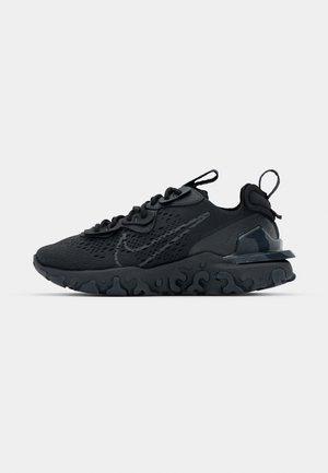 Black athletic shoe with a breathable mesh upper, textured accents, and a wavy rubber sole. Features reflective logo and lacing system.
