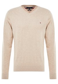 Beige V-Ausschnitt-Pullover aus weichem Material, mit gerippten Bündchen und Saum, sowie einem kleinen Logo auf der Brust.
