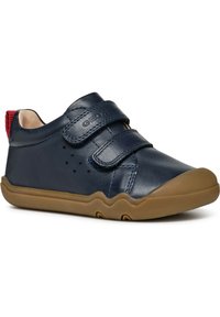 Marinblå lädersneakers med två kardborreband, gummisula och röd hälaccent. Har perforeringar för andningsförmåga och en rundad tå.