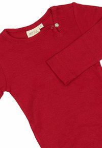 Giaccone rosso a coste con maniche lunghe, scollo rotondo e dettaglio con chiusura a pressione. Texture morbida, design aderente e accenti minimi.