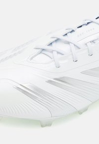 Witte voetbalschoenen met een strak ontwerp, gestructureerde bovenkant en zilveren accenten. Veters zichtbaar, met gevormde noppen voor grip.