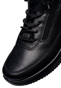 Black leather sneaker with smooth surface, round toe, and flat laces. Features fabric accents and a textured rubber sole for grip.