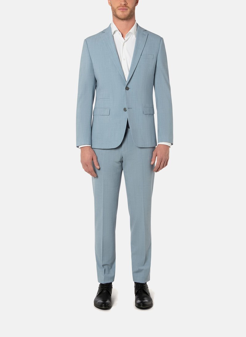 Vaaleansininen puku klassisella leikkauksella, jossa yksirivinen bleiseri, läppäkaulus ja mustat napit. Yhdistetty vastaaviin housuihin.