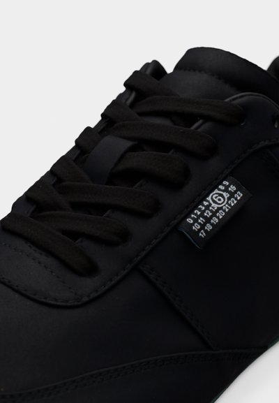 Κοντινό πλάνο μαύρου αθλητικού παπουτσιού με χοντρές κορδόνια και υφασμάτινη ετικέτα που δείχνει λευκούς αριθμούς από 0 έως 23, με τον αριθμό 6 να είναι κυκλωμένος.