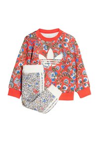 Červená kvetinová mikina s bielym logom Adidas a zodpovedajúce nohavice s bielym pásom a farebným kvetinovým vzorom po celom povrchu.