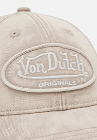 Bežna kapa od pamučne tkanine, s velikim izvezenim ovalnim pečatom s natpisima "Von Dutch" i "ORIGINALS" u bijelom koncu.