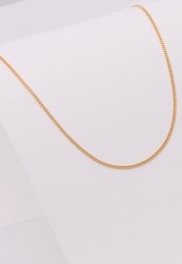 Gouden ketting met een ronde, dunne vorm. Kenmerkt zich door een gladde, glanzende textuur en uniforme schakels, rustend op een witte achtergrond.