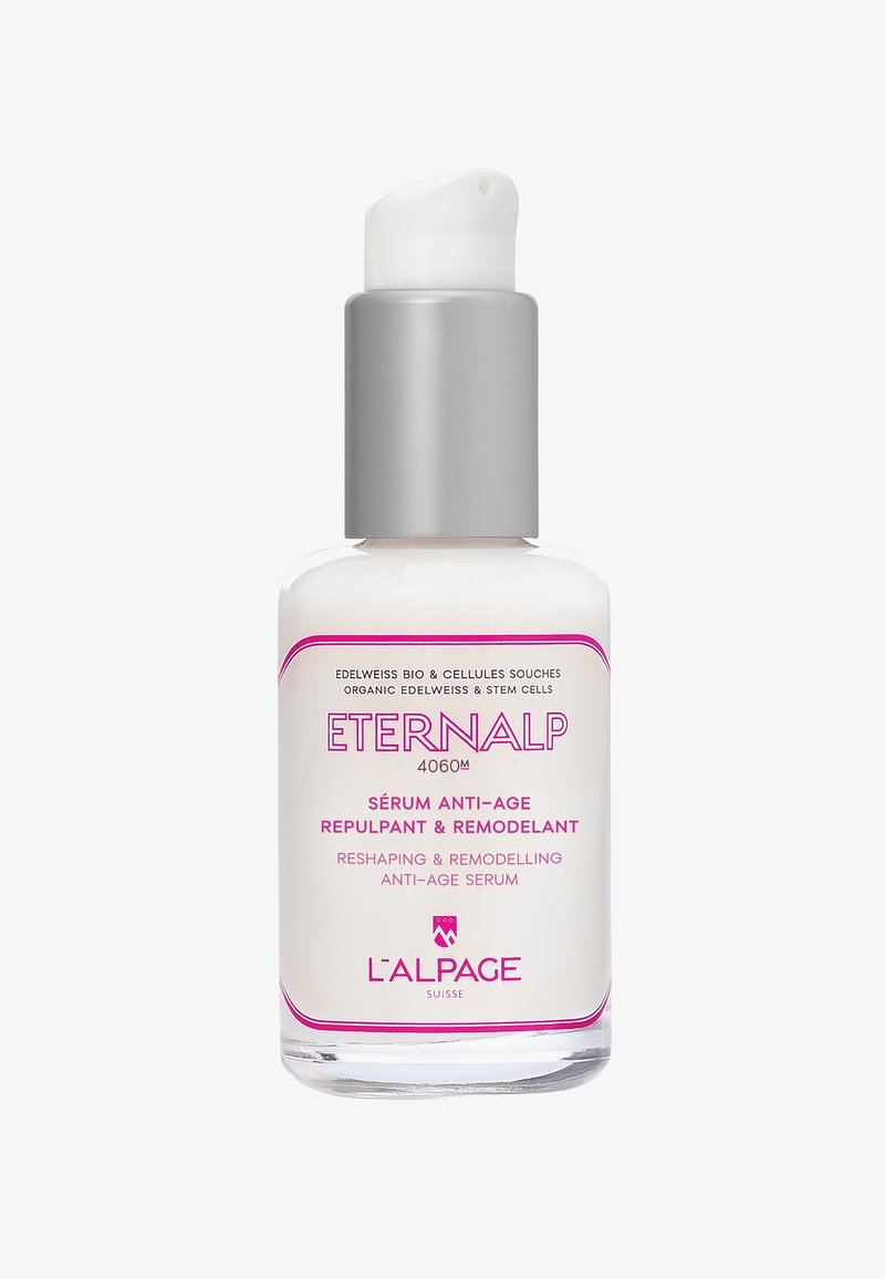 Flacon transparent avec pompe blanche et argentée contenant le sérum anti-âge L'Alpage Eternalp, avec un texte et un logo roses sur l'étiquette.