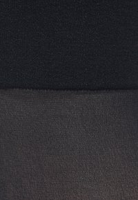 Svart ogenomskinlig överdel övergår till en genomskinlig svart nederdel. Slät textur med en enhetlig matt yta genomgående. Inga mönster eller dekorationer.