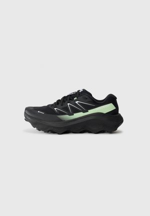Black and green Salomon running shoe with thick sole and aggressive tread, shown in left profile on white background.