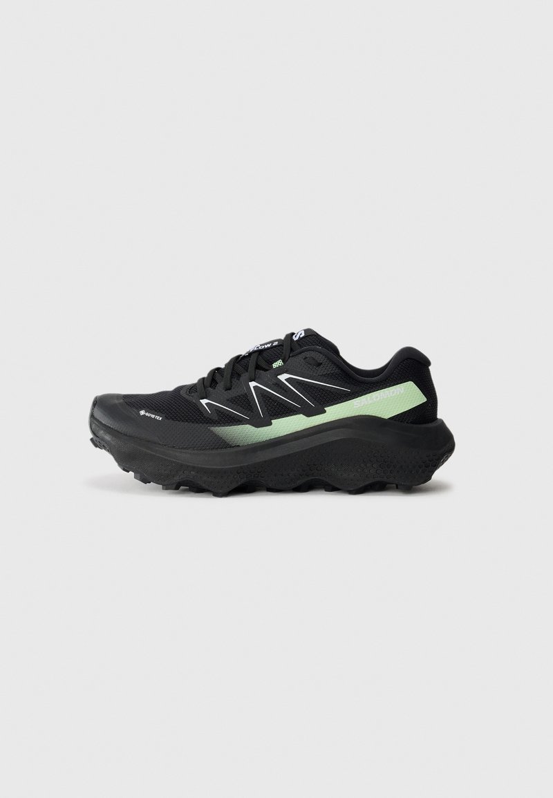 Black and green Salomon running shoe with thick sole and aggressive tread, shown in left profile on white background.