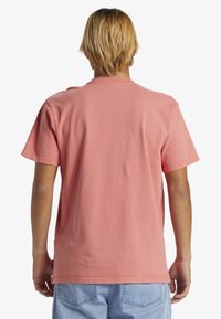 Tričko s krátkým rukávem v světle růžové barvě z bavlny, se standardním kulatým výstřihem, uvolněným střihem a rovnými okraji. Bez viditelného loga.