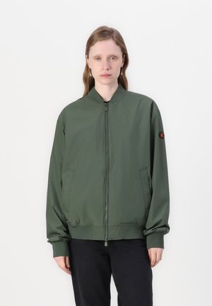 Groene bomberjack met een rits aan de voorkant, ribgebreide manchetten en twee zijzakken. Heeft een minimalistisch ontwerp en een ronde logo patch op de mouw.