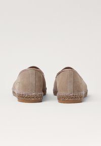 Beige suede espadrilles with woven jute accents on the sole. Rounded shape, elastic opening, and smooth texture. Minimal branding at the heel.