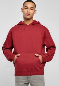 Felpa rossa in cotone con tasca frontale, caratterizzata da dettagli invecchiati, cappuccio con coulisse e polsini e orlo a coste.