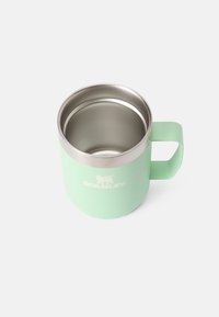 Taza aislante de color verde menta con interior de acero inoxidable, forma redondeada y asa resistente. Presenta un logotipo en el lado.