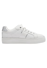 Sneaker blanc en cuir avec une semelle plateforme plate, présentant des accents argentés sur le talon, six œillets en métal et deux rayures décoratives sur les côtés.