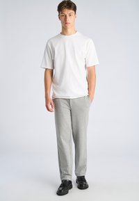 White cotton T-shirt paired with gray sweatpants. Model wears black shoes with tassels. Simple design without visible patterns or logos.