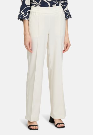 White, wide-leg pants with a smooth texture and an elasticized waistband, paired with black block-heeled sandals.