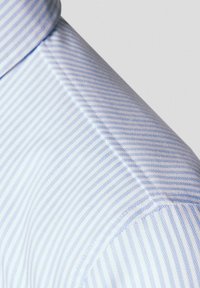 Jasnoniebieska koszula w paski, z kołnierzykiem i teksturowanym materiałem. Paski na przemian są jasnoniebieskie i białe, tworząc subtelny wzór.