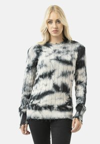 Knitted sweater with a black and white tie-dye pattern. Features ribbed cuffs and hem, textured cable design, and frayed edges.