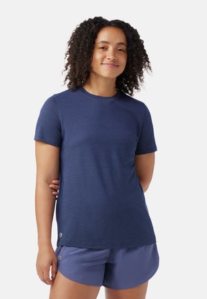 Navy blue short-sleeve top with textured fabric and round neckline. It features a subtle hem accent and paired with light purple shorts.