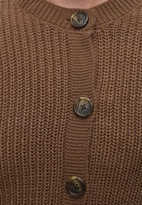 Pull tricoté marron avec de gros boutons marron attachés en rangée verticale au centre.