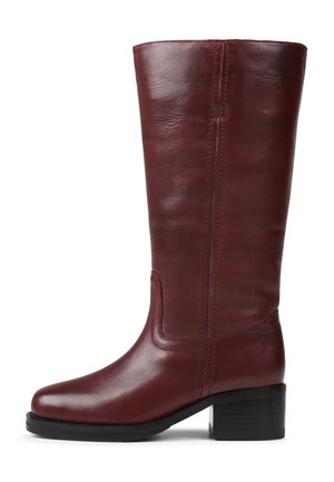 Botte en cuir bordeaux hauteur genou avec un bout arrondi, des coutures latérales discrètes et un petit talon bloc. Texture lisse et design classique.