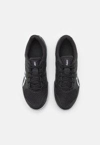 Baskets de sport noires avec une tige en mesh, bout rond et accents blancs. Présente une surface texturée et un système de laçage. La semelle a une légère courbure.