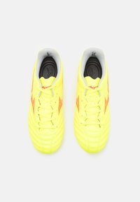 Scarpe da calcio giallo brillante con un design testurizzato, colletto imbottito, accenti rossi e chiusura con lacci. La suola è leggermente arrotondata.