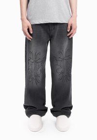 Temno sive jeans hlače iz jeansa z ohlapnim krojem, ki imajo na sprednji strani črne vezenine, oblikovane s pravokotno širino nogavic in enostavnim robom.