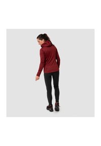 Jachetă cu glugă de culoare vișinie într-un design ajustat, asortată cu colanți negri și încălțăminte texturată neagră. Costumul are mâneci lungi și o siluetă elegantă.