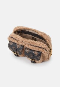 Béžová taška přes rameno ze shearlingu s dvěma předními kapsami se sponou z černé vzorované koženky a zlatým zipem částečně otevřeným, odhalujícím značkový interiér.