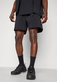 Black athletic shorts with a loose fit, paired with black crew socks and black sneakers. The fabric appears lightweight and flexible.