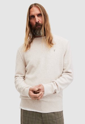 Light beige sweater made of soft, textured fabric, featuring a crew neckline and ribbed cuffs, with a small embroidered logo on the chest.