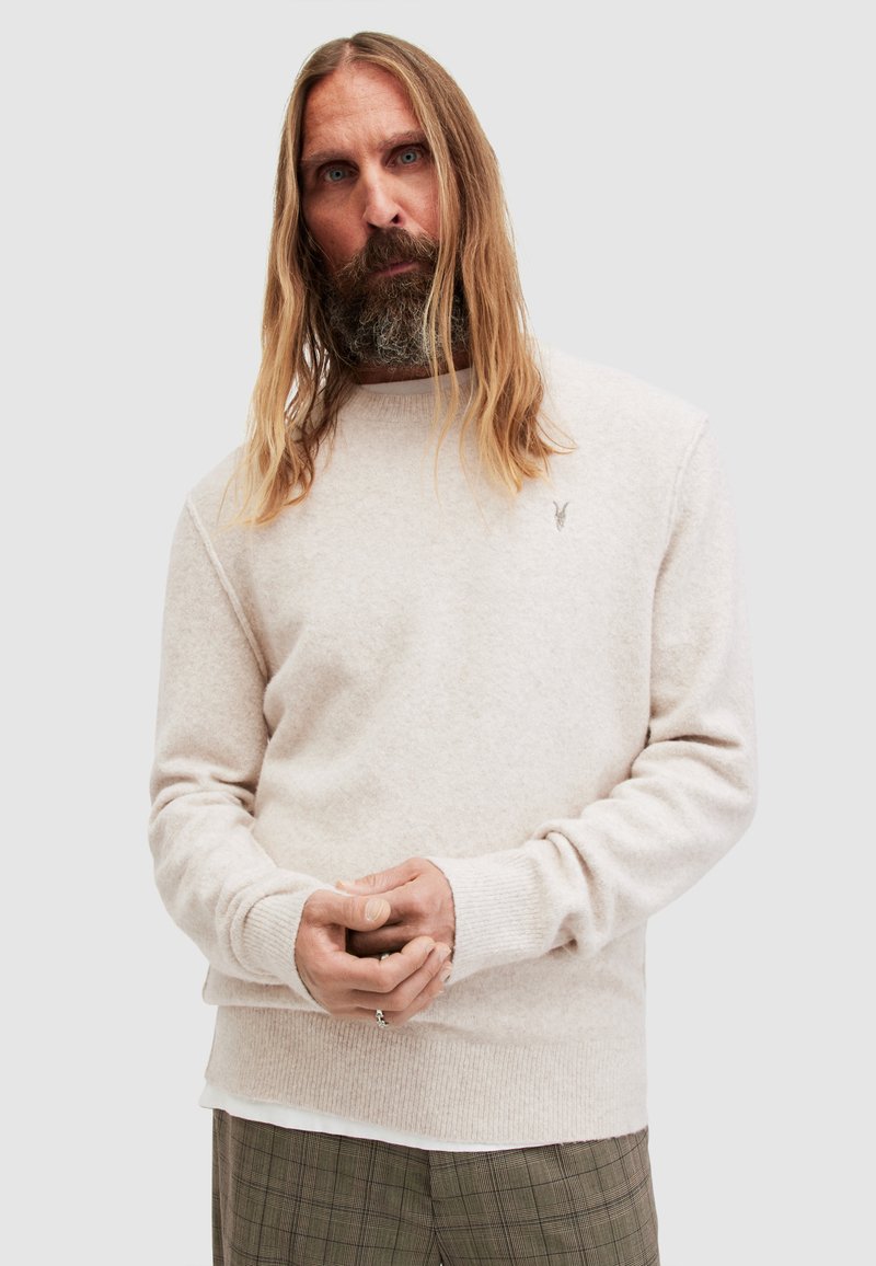 Hellbeige Pullover aus weichem, strukturiertem Stoff, mit Rundhalsausschnitt und gerippten Bündchen, versehen mit einem kleinen gestickten Logo auf der Brust.