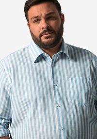 Ljusblågul och vitrandig skjorta med knappar i bomull. Har krage, långa ärmar och en bröstficka.