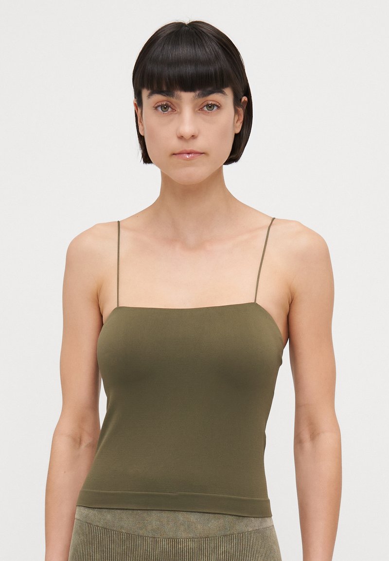 Camisola verde oliva con spalline sottili, design aderente, tessuto morbido e scollo dritto, abbinata a una sottile trama a coste all'orlo.