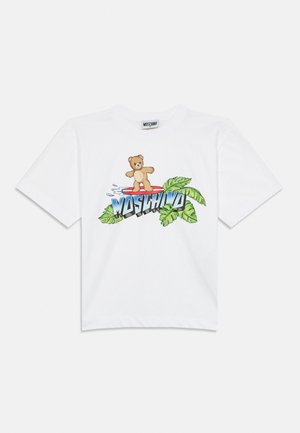 Bijela majica s grafikonom medvjedića koji surfa na crvenoj dasci iznad plavog natpisa "MOSCHINO" i zelenih tropskih listova.