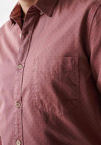 Camicia a maniche corte bordeaux con bottoni, dotata di taschino sul petto, caratterizzata da un motivo discreto di piccole macchie navy e un design del colletto classico.
