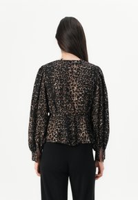 Bluzica sa leopard printom s skupljenim pojasom, dugim puff rukavima i okruglim izrezom, izrađena od lagane tkanine u crnim i smeškim nijansama.