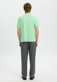 Mintgrøn bomulds t-shirt med korte ærmer, parret med grå skræddersyede bukser; flad tekstur, afslappet pasform, enkelt design uden grafik.