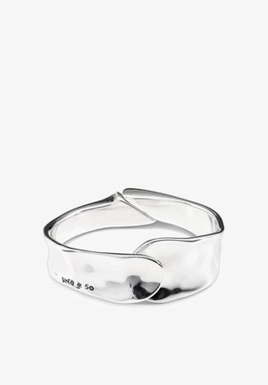 Bracelet en argent présentant un design lisse et courbé avec un détail torsadé qui se chevauche. Fini poli avec un minimum de gravure.