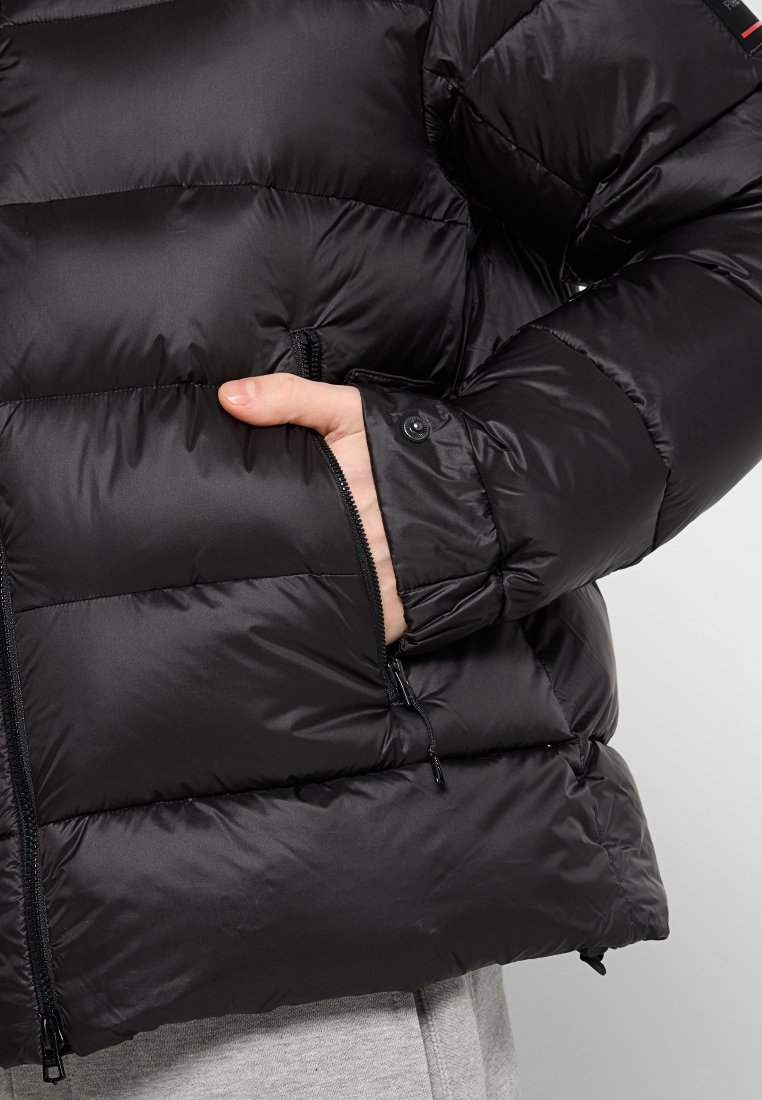 Schwarze, gefütterte Jacke mit einer Reißverschlusstasche, gestepptem Muster, leichtem Material und einem knopfverschlossenen Ärmeldetail.