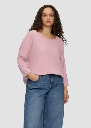 Haut à manches longues côtelé rose clair avec un large col, coupe décontractée et épaules tombantes, associé à un jean en denim bleu ample.